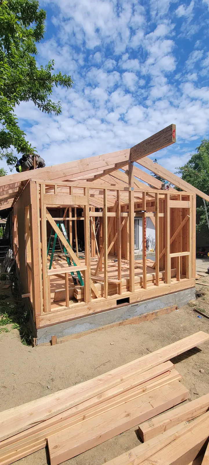 Home addition framing in progress with new structure and roof framing by Lions Gate Remodeling