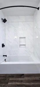 Bathroom remodel in Oakland CA featuring white marble tile tub surround and black fixtures