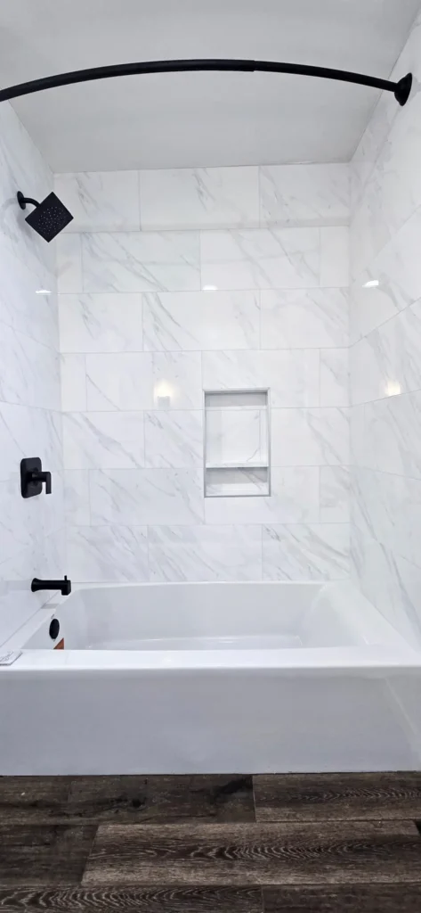 Bathroom remodel in Oakland CA featuring white marble tile tub surround and black fixtures