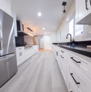 Modern galley kitchen remodel in Oakland, CA with white shaker cabinets, black countertops, and stainless steel appliances