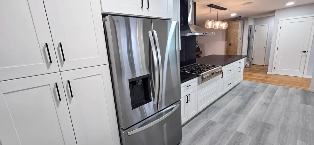 White shaker kitchen cabinets with black hardware and stainless steel refrigerator in Oakland, CA remodel