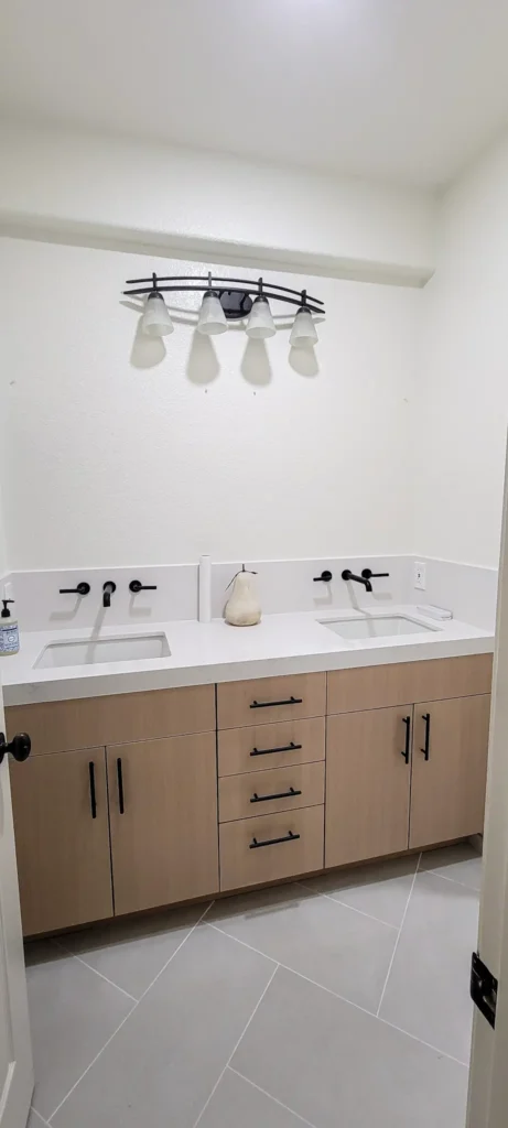 Guest bathroom remodel in Pleasanton CA featuring double sink vanity, quartz countertop, light wood cabinetry, and matte black fixtures by Lions Gate Remodeling.