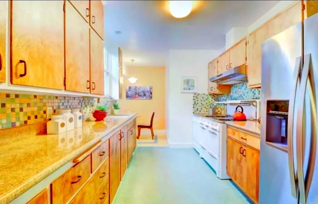 Before kitchen remodel in Walnut Creek showing a narrow galley kitchen with older cabinets, laminate counters, and mosaic tile backsplash