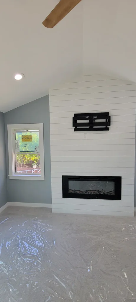 Finished master bedroom from a home addition in Martinez California featuring a modern built-in fireplace and shiplap accent wall