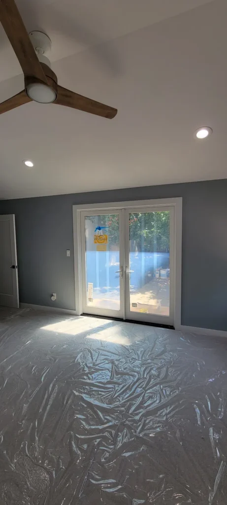 Finished master bedroom from a home addition in Martinez California with vaulted ceiling, ceiling fan, recessed lighting, and patio doors