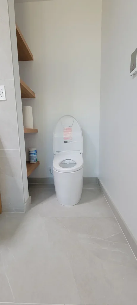 Modern toilet area in a master bathroom addition in Martinez California with built in wood shelving and tile flooring