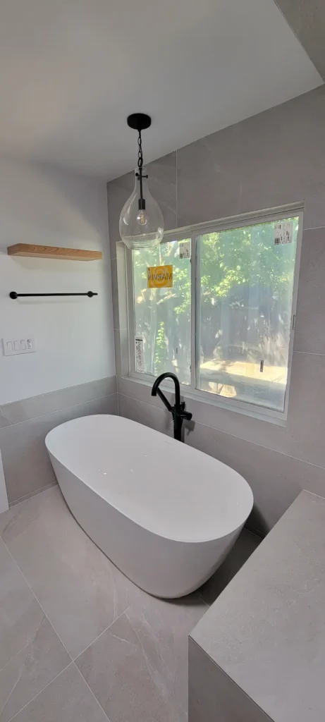 Freestanding soaking tub in a custom master bathroom addition in Martinez California with modern tile and black fixtures