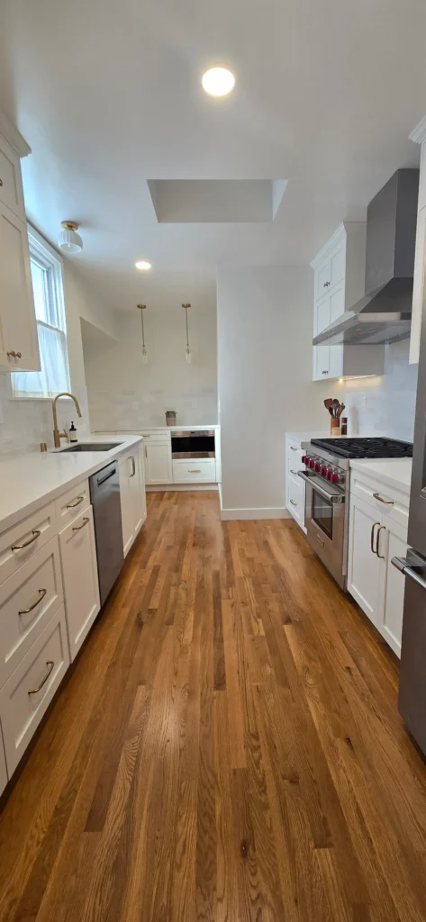 Finished Walnut Creek kitchen remodel with white shaker cabinets, hardwood flooring, stainless steel appliances, and skylight bringing natural light into the space