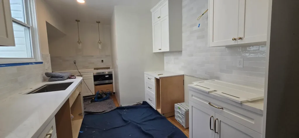 Walnut Creek kitchen remodel during installation with white shaker cabinets, brass hardware, and tile backsplash being completed